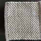 Square of fabric with a herringbone pattern on a dark background