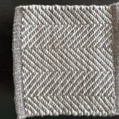 Square of fabric with a herringbone pattern on a dark background
